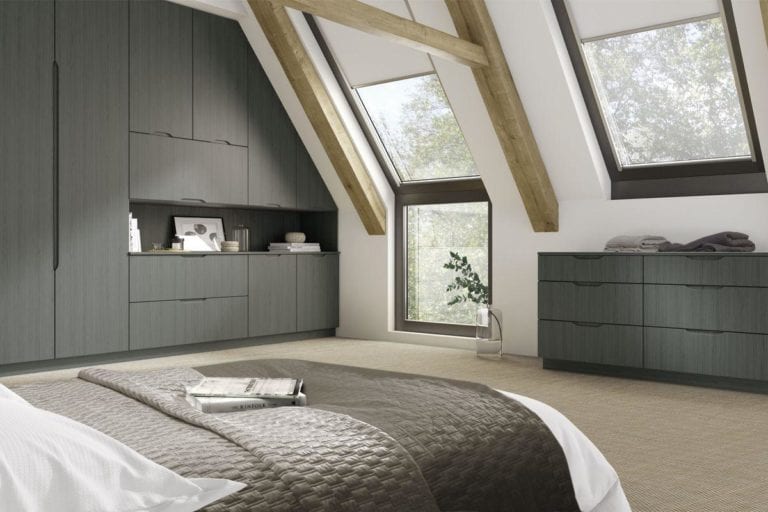 Large, open bedroom with exposed beams, dark grey built in wardrobes & roof windows