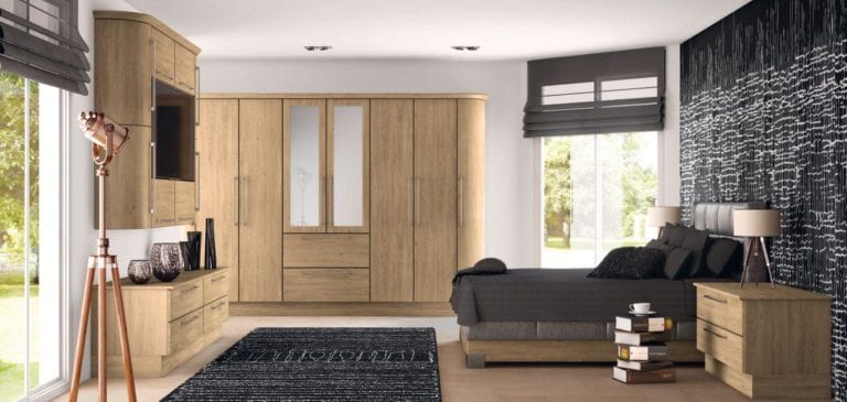 Bedroom with light brown wooden wardrobes, white walls, dark grey bed, long windows & copper standing light