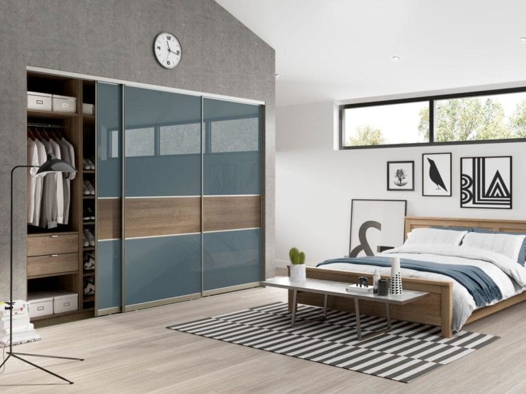 Modern bedroom with grey & white walls, a wooden framed bed & built in sliding wardrobe with blue glass doors